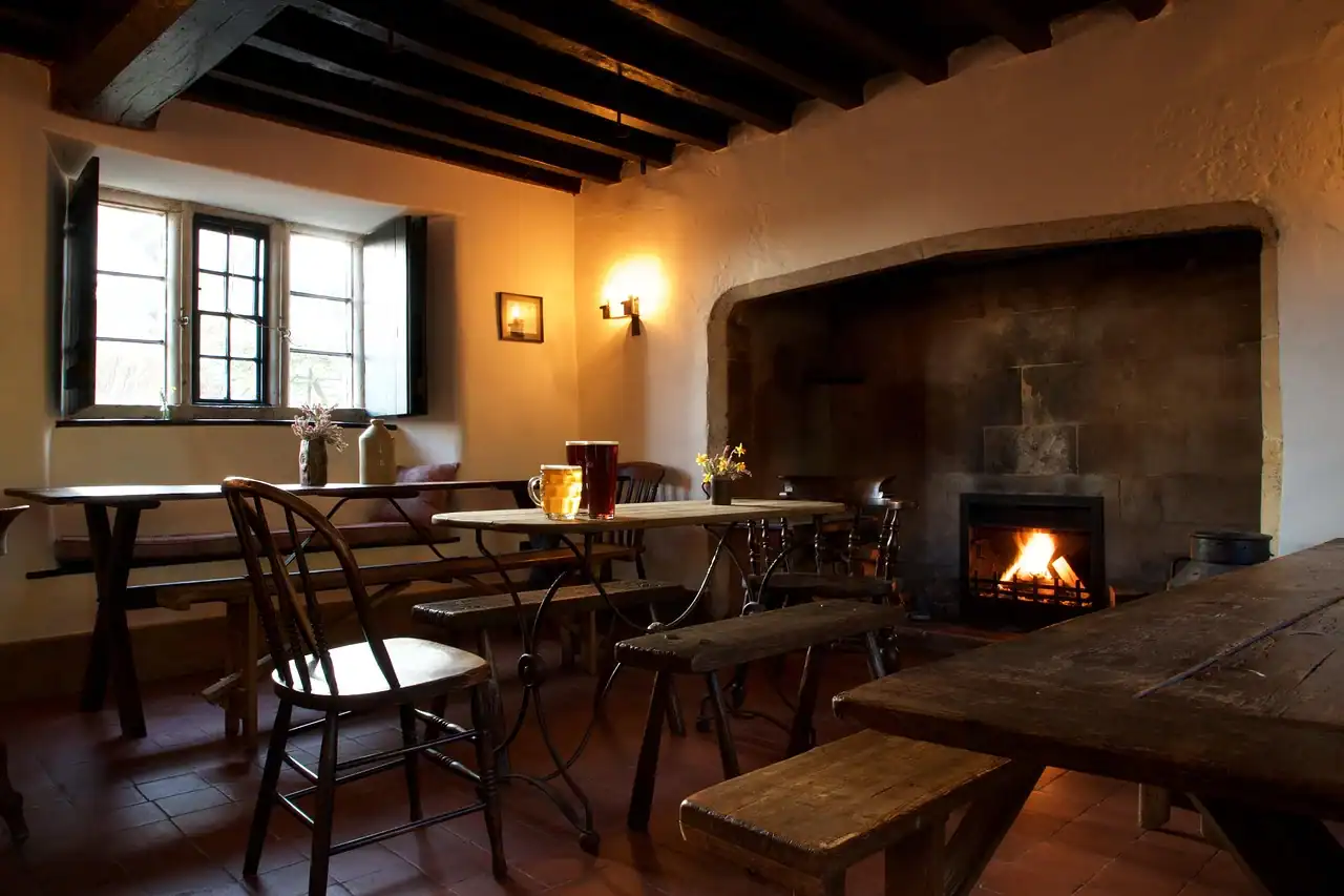 Interior de hotel con chimenea, luz cálida y mesas de madera; un lugar perfecto para pensar tras una travesía.